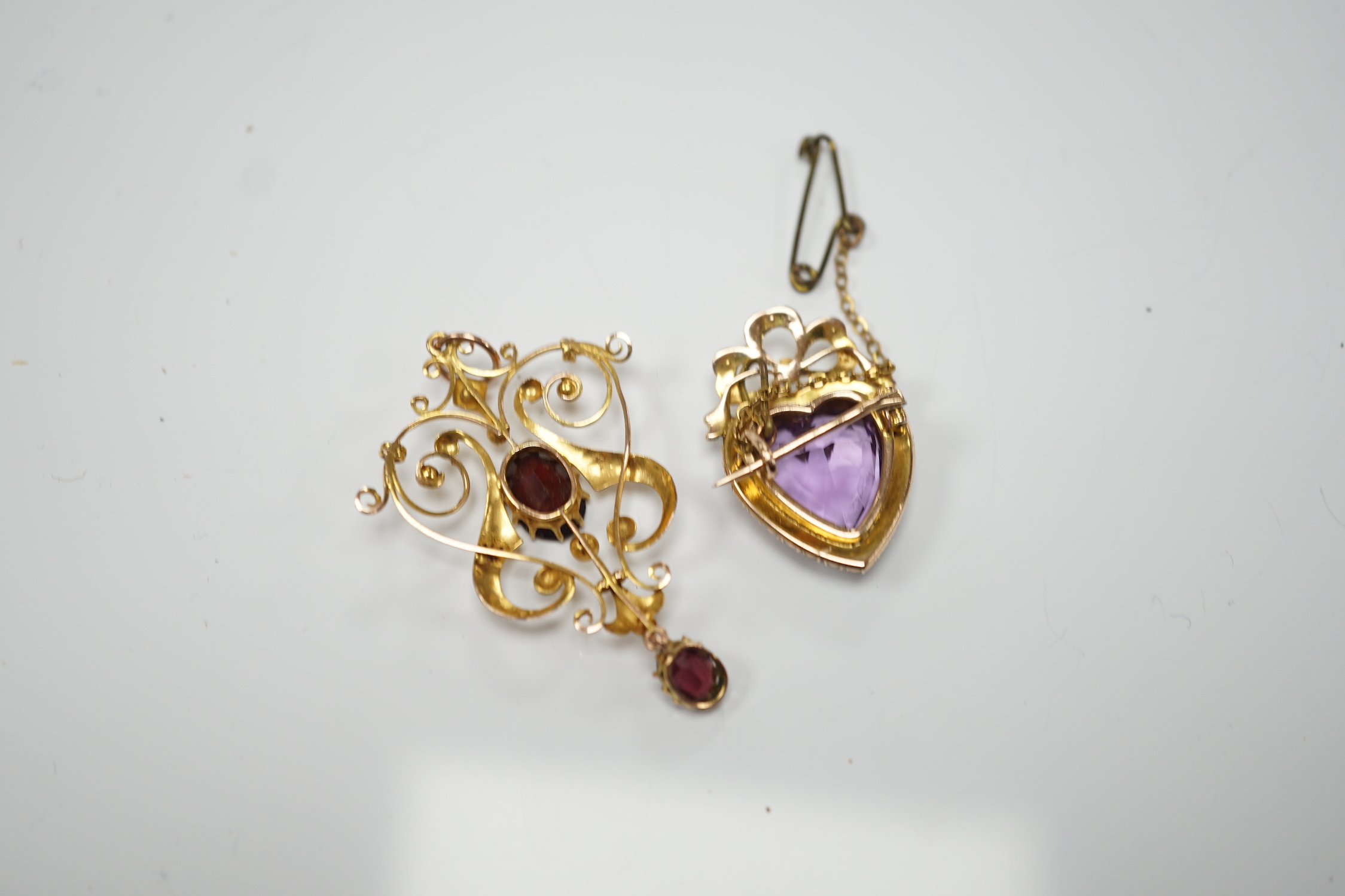 An early 20th century yellow metal, amethyst and seed pearl cluster set heart shaped brooch, 27mm, together with a similar yellow metal and two stone garnet set drop pendant, gross weight 9.3 grams.